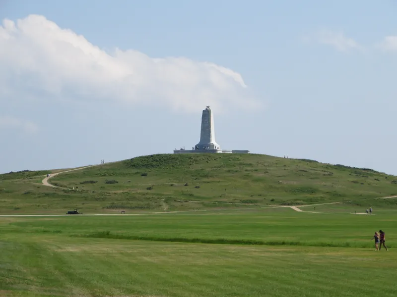 Wright Brothers National Memorial Visitor Center with monument tower visible on the hill behind it