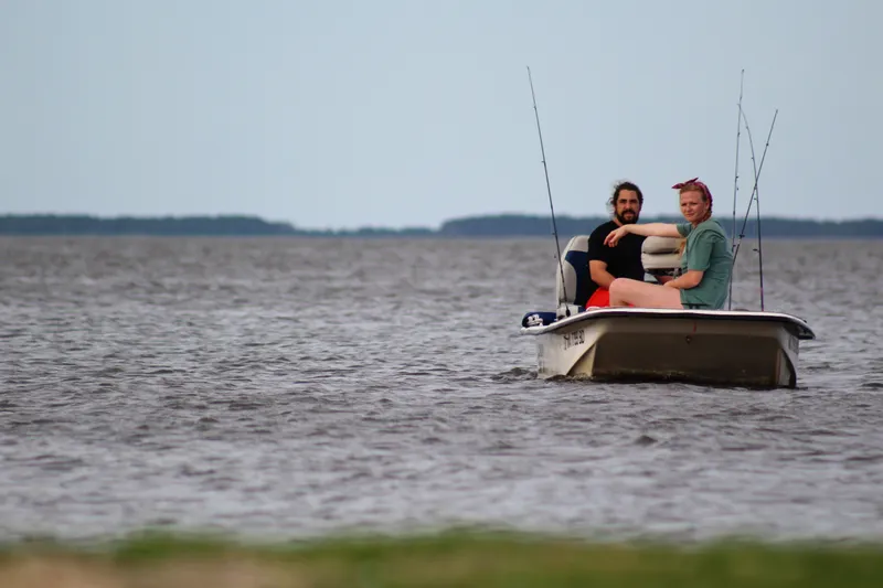 Person walking along the shore at sunset on a remote section of the Outer Banks, with golden light reflecting off wet sand