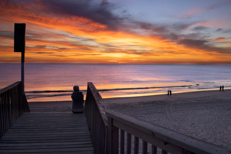 Soft golden sunrise light illuminating the ocean and sand at Corolla Beach with colorful clouds overhead